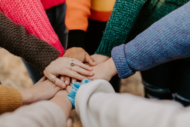 People putting their hands together in the center of a huddle